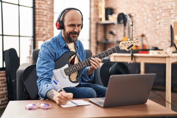 Wall Mural - Young bald man musician composing song at music studio