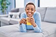 © Krakenimages.com - African american woman drinking coffee lying on sofa at home