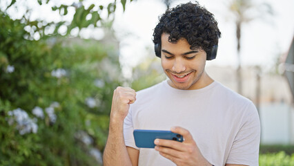 Poster - Young latin man watching soccer game with winner gesture at park