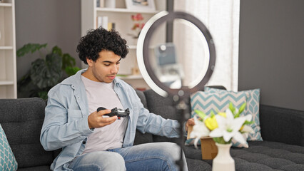 Canvas Print - Young latin man unpacking joystick of cardboard box recording video tutorial at home