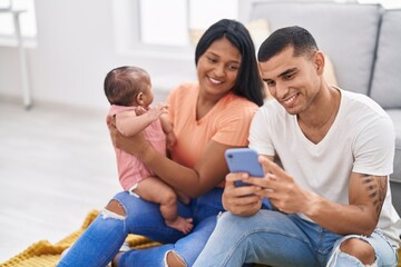 Poster - Hispanic family using smartphone sitting on floor at home