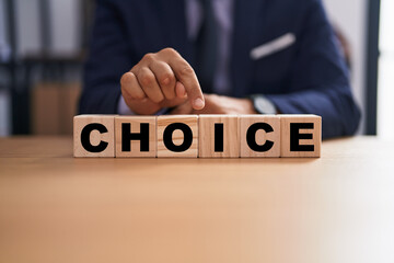 Business man holding cubes with choice word on the table