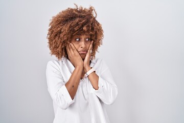 Sticker - Young hispanic woman with curly hair standing over white background tired hands covering face, depression and sadness, upset and irritated for problem