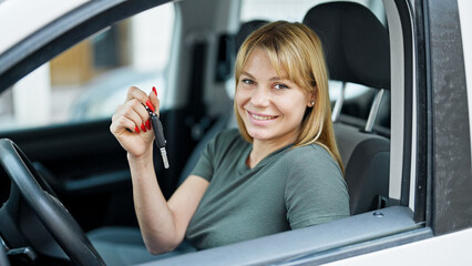 Wall Mural - Young blonde woman smiling confident holding key of new car at street