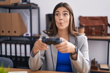 Canvas Print - Hispanic woman working at the office playing video games making fish face with mouth and squinting eyes, crazy and comical.