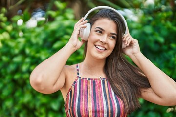 Poster - Young beautiful hispanic woman listening to music at park