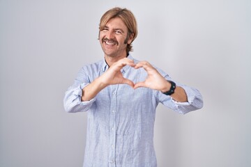 Canvas Print - Caucasian man with mustache standing over white background smiling in love doing heart symbol shape with hands. romantic concept.