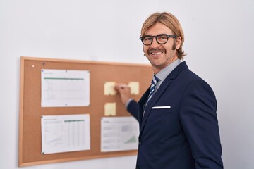 Poster - Young blond man business worker writing on cork board at office