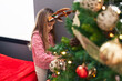 © Krakenimages.com - Adorable blonde girl wearing reindeer ears decorating christmas tree at home