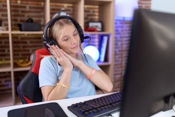 Sticker - Young caucasian woman playing video games wearing headphones sleeping tired dreaming and posing with hands together while smiling with closed eyes.