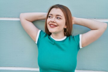 Poster - Young redhead woman smiling confident standing with hands on head over isolated green wall