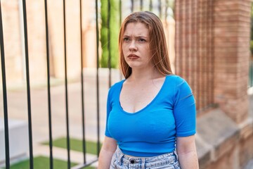 Poster - Young redhead woman looking to the side with serious expression at street