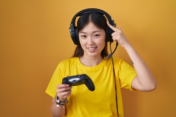 Sticker - Chinese young woman playing video game holding controller smiling pointing to head with one finger, great idea or thought, good memory