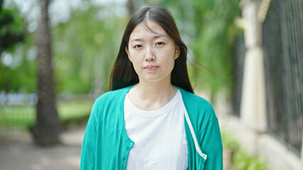 Sticker - Young chinese woman standing with serious expression at park