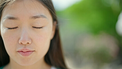 Sticker - Young chinese woman breathing with closed eyes at park