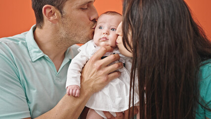 Family of three kissing sitting on the sofa at home