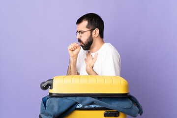 Traveler caucasian man with a suitcase full of clothes over isolated purple background coughing a lot