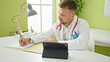 © Krakenimages.com - Young man doctor using touchpad writing medical report at clinic