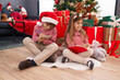 © Krakenimages.com - Brother and sister drawing on notebook sitting on floor by christmas tree at home