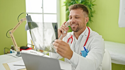 Canvas Print - Young man doctor talking on telephone holding xray at clinic