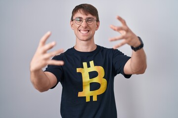 Sticker - Caucasian blond man wearing bitcoin t shirt shouting frustrated with rage, hands trying to strangle, yelling mad