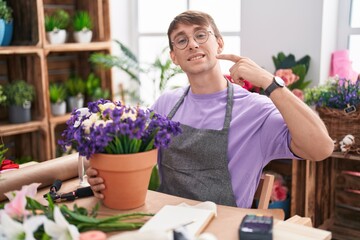 Canvas Print - Caucasian blond man working at florist shop smiling cheerful showing and pointing with fingers teeth and mouth. dental health concept.