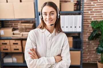 Canvas Print - Young caucasian woman working at small business ecommerce wearing headset happy face smiling with crossed arms looking at the camera. positive person.