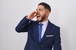 © Krakenimages.com - Young hispanic man wearing business suit and tie shouting and screaming loud to side with hand on mouth. communication concept.