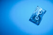 © Trik - Transparent audio cassette tape photo on blue background. Place for text.
