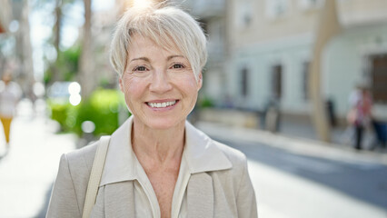 Wall Mural - Middle age blonde woman smiling confident standing at street