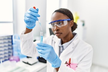 Canvas Print - African american woman scientist pouring liquid on test tube at laboratory