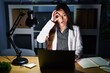 © Krakenimages.com - Young brunette woman working at the office at night with laptop doing ok gesture shocked with surprised face, eye looking through fingers. unbelieving expression.