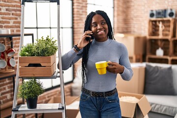 Poster - African american woman talking on smartphone drinking coffee at new home