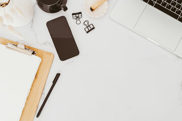 White desk office copy space with laptop, smartphone with black screen, stationery and notepads, cup of tea and palo santo