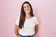 Young brunette woman standing over pink background with a happy and cool smile on face. lucky person.