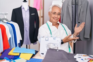 Poster - Middle age man with grey hair dressmaker using sewing machine inviting to enter smiling natural with open hand