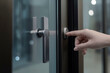 a hand reaching out to press a silver, round doorbell on a modern, black glass door, ai generative