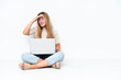 © luismolinero - Young woman with laptop sitting on the floor isolated on white background looking far away with hand to look something