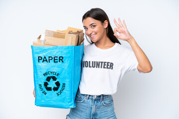 Wall Mural - Young caucasian woman holding a recycling bag full of paper to recycle isolated on white background showing ok sign with fingers