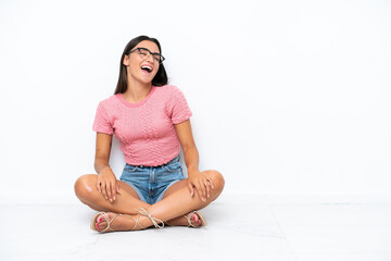 Wall Mural - Young caucasian woman sitting on the floor isolated on white background laughing in lateral position