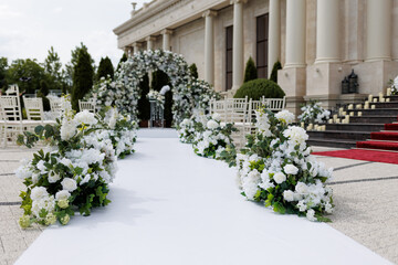 Wall Mural - Wedding ceremony outdoor. A beautiful and stylish wedding arch, decorated by various fresh white flowers with white chairs, standing in the garden. Celebration day.