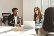 © Maria Vitkovska - Group of confident entrepreneurs sitting at the desk workplace working together