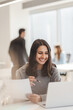 © Maria Vitkovska - Smiling young indian woman, entrepreneur holding documents while working on laptop