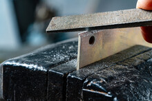 Craftsman Works On Small Piece Of Metal With Metal File Gripped In Vise On Workbench Table In Garage Workshop, Do It Yourself Concept, Closeup