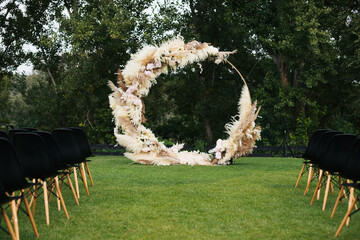 Wall Mural - Round wedding arch decorated with reeds with black chairs. Wedding ceremony in the forest outdoor
