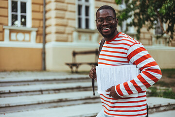 Wall Mural - Authentic portrait of young successful African American man wearing stylish eyeglasses, standing on the street. Handsome asian model posing for pictures, looking at camera, smiling