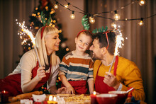A Festive Family Celebrating Christmas And New Year At Home With Fireworks While Making Gingerbread Cookies.