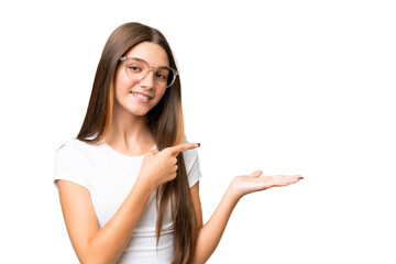 Poster - Teenager caucasian girl over isolated background holding copyspace imaginary on the palm to insert an ad