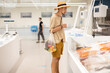 © rh2010 - Stylish man in hat choosing fresh fish to buy at modern supermarket. Concept of healthy sea food and shopping
