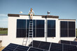 © rh2010 - Rooftop of a private house with solar power station on it, man sitting on a top and enjoys his property. Concept of renewable energy and sustainable lifestyle